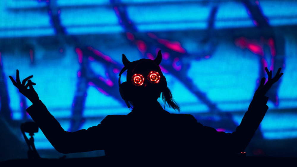 Rezz on stage with her hands up wearing her glasses