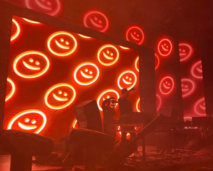 Shot of Darren Styles performing in Vancouver BC indoors with red lights and red smiley face visuals.