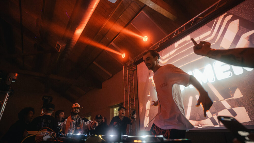 Bommer performing at the Freight House with red lights and his logo on screen